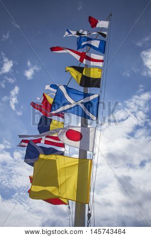international maritime signal flags jn a flagpole against a blue sky