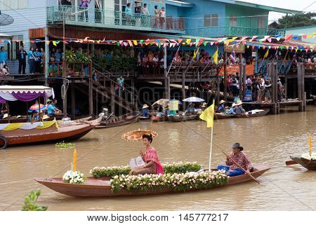 AYUTTHAYA, THAILAND - JULY 15, 2011: Pretty woman sitting show on the flower boats in candle floating parade, the unique annual candle festival of Buddhist lent  in Lad Chado, Ayutthaya, Thailand.