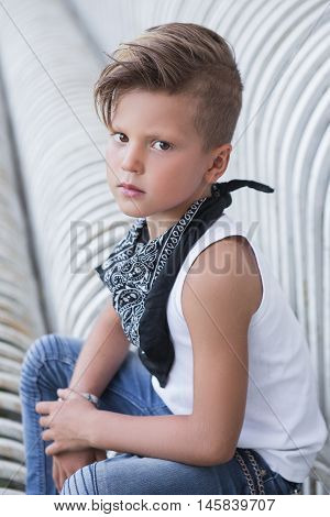 Stylish little boy sitting with a serious expression . It is very stylish . Children's emotions