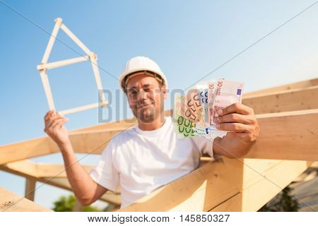 Young man with Euro banknotes and a symbolic house in his hands