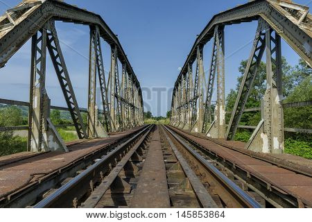 Old metal railroad bridge over the river. Detailed view.