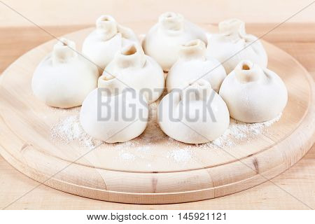 Manti dumplings on the a wooden board.