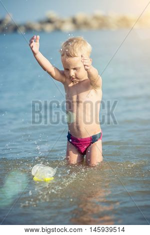 Little boy with snorkel by the sea. Cute little kid wearing mask and flippers for diving at sand tropical beach. Ocean coast.