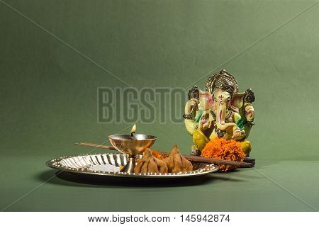 Hindu God Ganesha. Statue of Lord Ganesha. Pooja arrangement on green background.