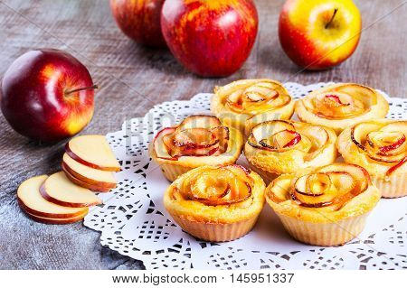 Apple shaped roses muffins on rustic wooden table. Sweet apple dessert pie. Homemade apple rose pastry.