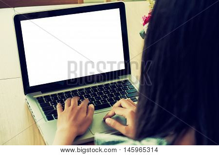 Close up of young woman using laptop computer on wooden table with blank screen laptop computer.Business concept.Young woman hands holding keyboard.Vintage tone