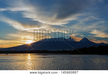 Beautiful sunrise over the volcanoes Kluchevskaya group with reflection in the river Kamchatka.