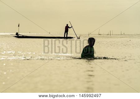 Silhouettes of the traditional stilt fishermen at sunset