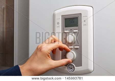 Men hand regulate temperature on 55 degree in control panel of DHW.