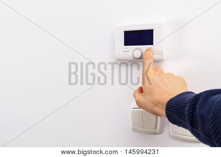 Men hand setting the temperature on control panel of DHW or central heating.