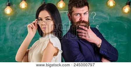 Man With Beard And Teacher In Eyeglasses Stand Back To Back, Chalkboard On Background. Teacher And S