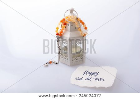 The Word Eid El Fitr   On Torn Paper Beside A Lantern And Prying Beads