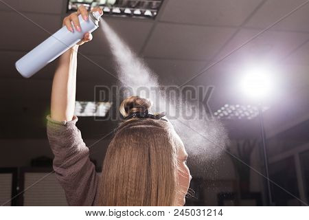 Hairdresser Fixing A Coiffure With A Topknot Of A Young Beautiful Model Using A Hair Spray In A Beau