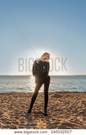 Attractive Slender Person Girl Blonde Stands Posing On The Shore Of The Water In Black Clothes With 