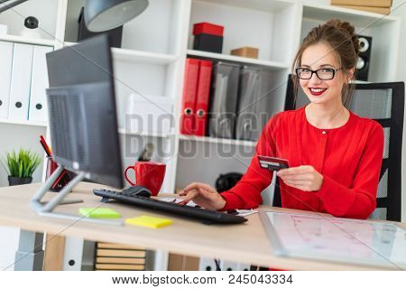 Beautiful Young Girl In Glasses And A Red Shirt Is Working In The Office. Photo With Depth Of Field.