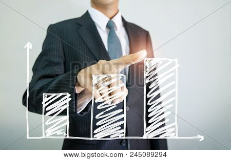 Businessman Drawing Graphics A Growing Graph Lighting On Background
