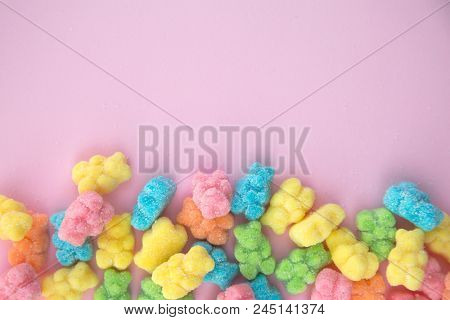 Delicious and colorful gummy bears on a pink background