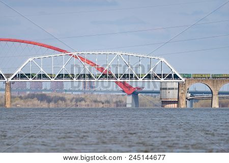 A Freight Train Is Driving Across A Bridge Across The River