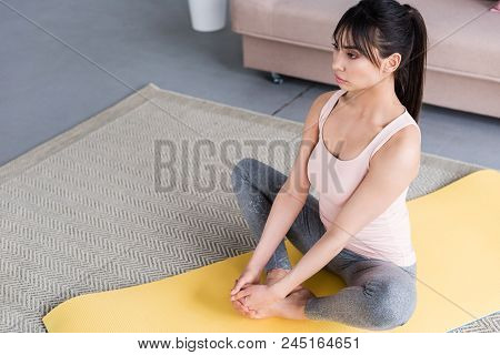 High Angle View Of Beautiful Young Woman Practicing Yoga In Bound Angle Pose At Home