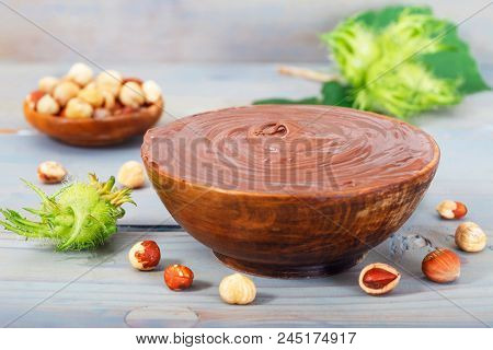 Sweet Chocolate Hazelnut Spread With Whole Nuts And Green Hazelnut On Blue Table. Nutella Cream.
