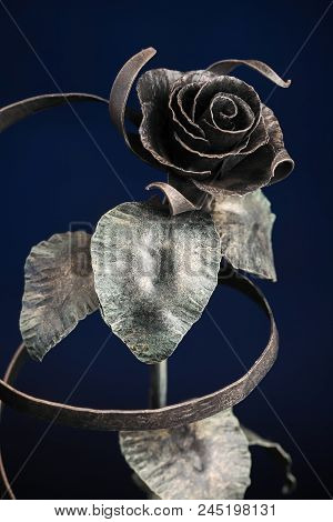 The Broze Rose With A Tape Made Of Metal, On Dark-blue Background.