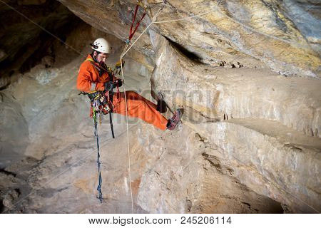 Speleologist performing rope maneuvers in a cave. Zaragoza Province, Aragon, Spain.
