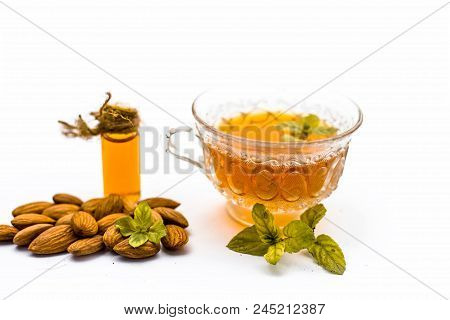 Beneficial And Essential Oil Of Badam Or Almonds With Its Beneficial Tea In A Transparent Cup Isolat