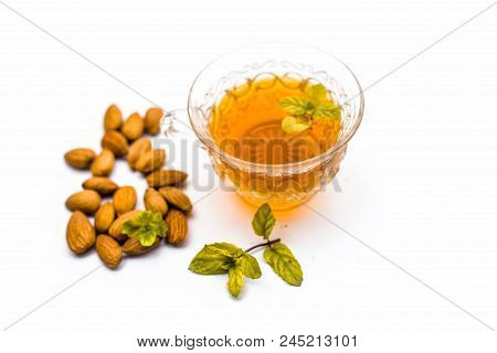 Beneficial And Essential Oil Of Badam Or Almonds With Its Beneficial Tea In A Transparent Cup Isolat