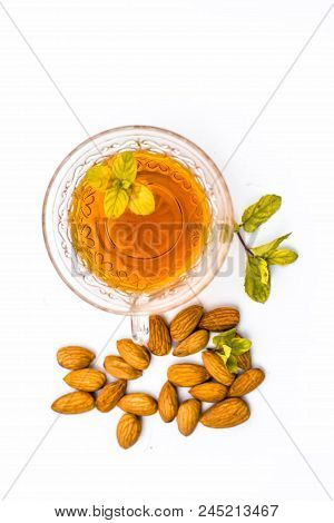 Beneficial And Essential Oil Of Badam Or Almonds With Its Beneficial Tea In A Transparent Cup Isolat