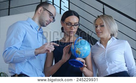 Three Teachers Discuss Something With Globe. Professional Shot In 4k