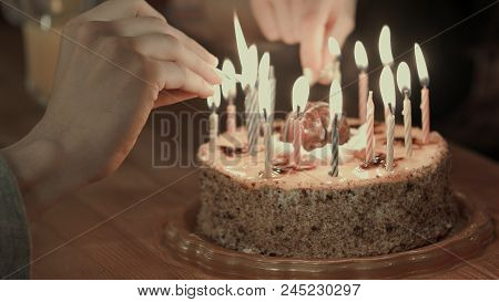 Two People Lighting The Candels On A Birthday Cake. Close