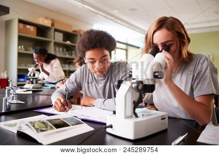 High School Students Looking Through Microscope In Biology Class