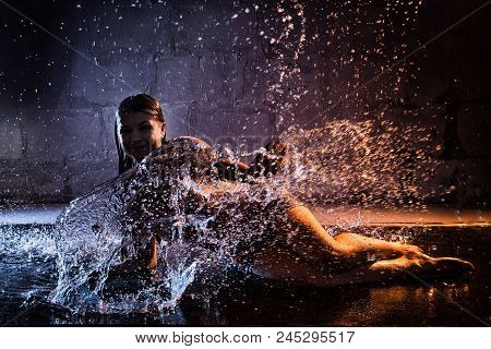 Girl Brunette With Wet Hair In The White Shirt, Water Drops Around And Dark Wall Background Illumina