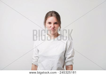 Portrait Of An Upset Unsatisfied European Woman. She Is Frowning Her Nose In Irritated Mood. Negativ