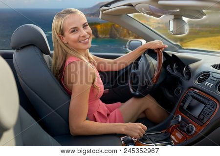 travel, road trip and people concept - happy young woman driving convertible car over bixby creek bridge on big sur coast of california background