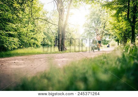 Running Woman With Baby Stroller Enjoying Summer Day In Park. Jogging Or Power Walking Supermom, Act