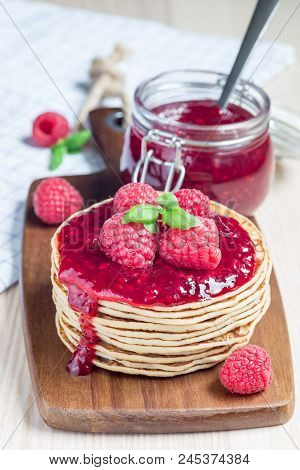 Stack Of Pancakes Or Fritters With Raspberry Jam And Berries On A Wooden Board, Verical