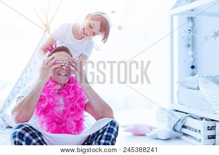Guess Who. Smiling Preteen Daughter Closing Eyes Of Her Thoughtful Daddy Wearing A Bright Feather Bo