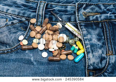 Pills Or Medicine Tablets Scattered On Jeans Near Zip, Denim Background. Genitourinary Problem Conce