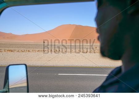 View Through Vehilce Window Of Bright Red Dramatic Dunes Along Road In Sossusvlei Namibia