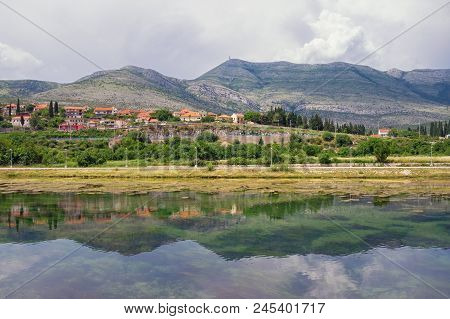 Landscape With Hills, Mountains And Small Town On River Bank Is Reflected In Water. Bosnia And Herze