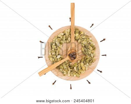 Two Wooden Spoons With Cloves And Seeds, Lying On The Wooden Board That Looks Like Round Clock With 