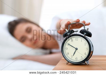 Sleepy Young Woman Stretching Hand To Ringing Alarm Willing Turn It Off. Early Wake Up, Not Getting 