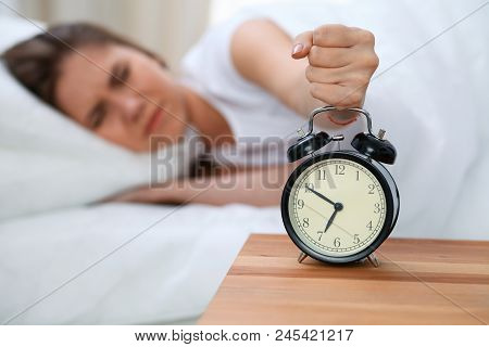 Sleepy Young Woman Stretching Hand To Ringing Alarm Willing Turn It Off. Early Wake Up, Not Getting 