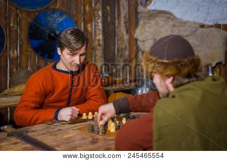 Two Men In Russian Ethnic Suit Playing Medieval Popular Strategy Board Game - Tafl. Folk, Competitio