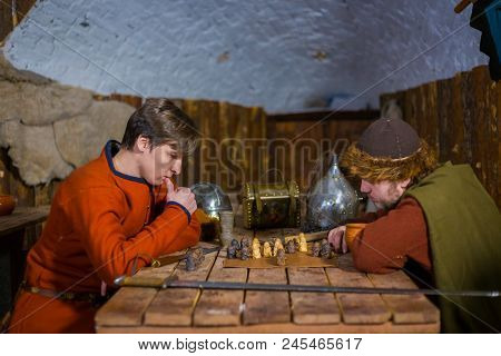 Two Men In Russian Ethnic Suit Playing Medieval Popular Strategy Board Game - Tafl. Folk, Competitio