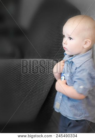 Portrait Of A Small 1, 5 Years Old Baby Boy Standing In Dark Roon Under Wall And Looking Scared. Fea