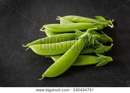 Freshly picked snow peas on a black background.