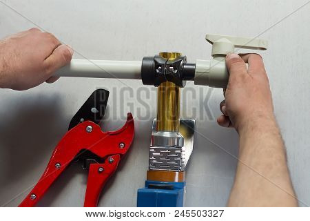 Soldering Iron For Polypropylene Plumbing Pipes. The Hands Of The Plumber Are Holding The Pipeline P