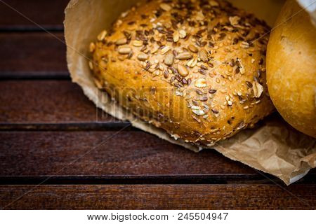Fresh Baked Bread Wrapped In Paper, On Wooden Background